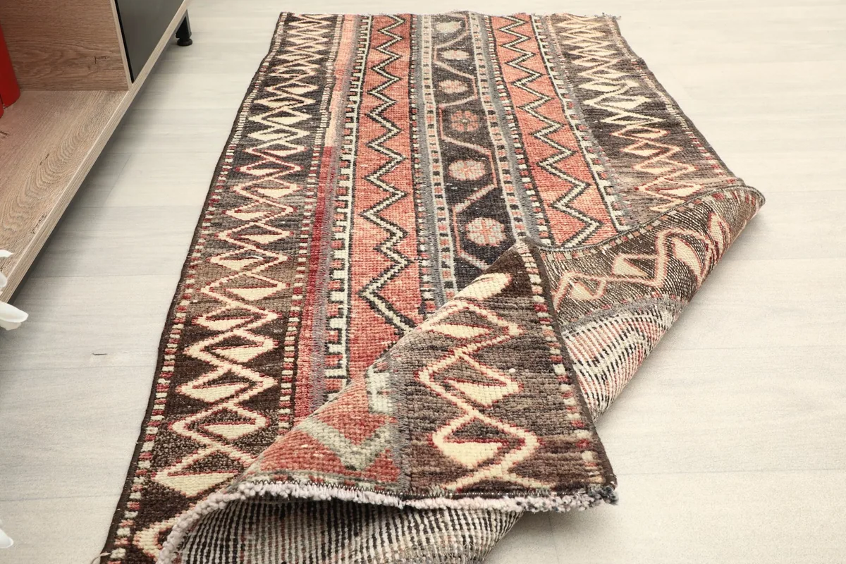 Partial view of the rug with a corner folded back, showing the back of the rug and its thickness.