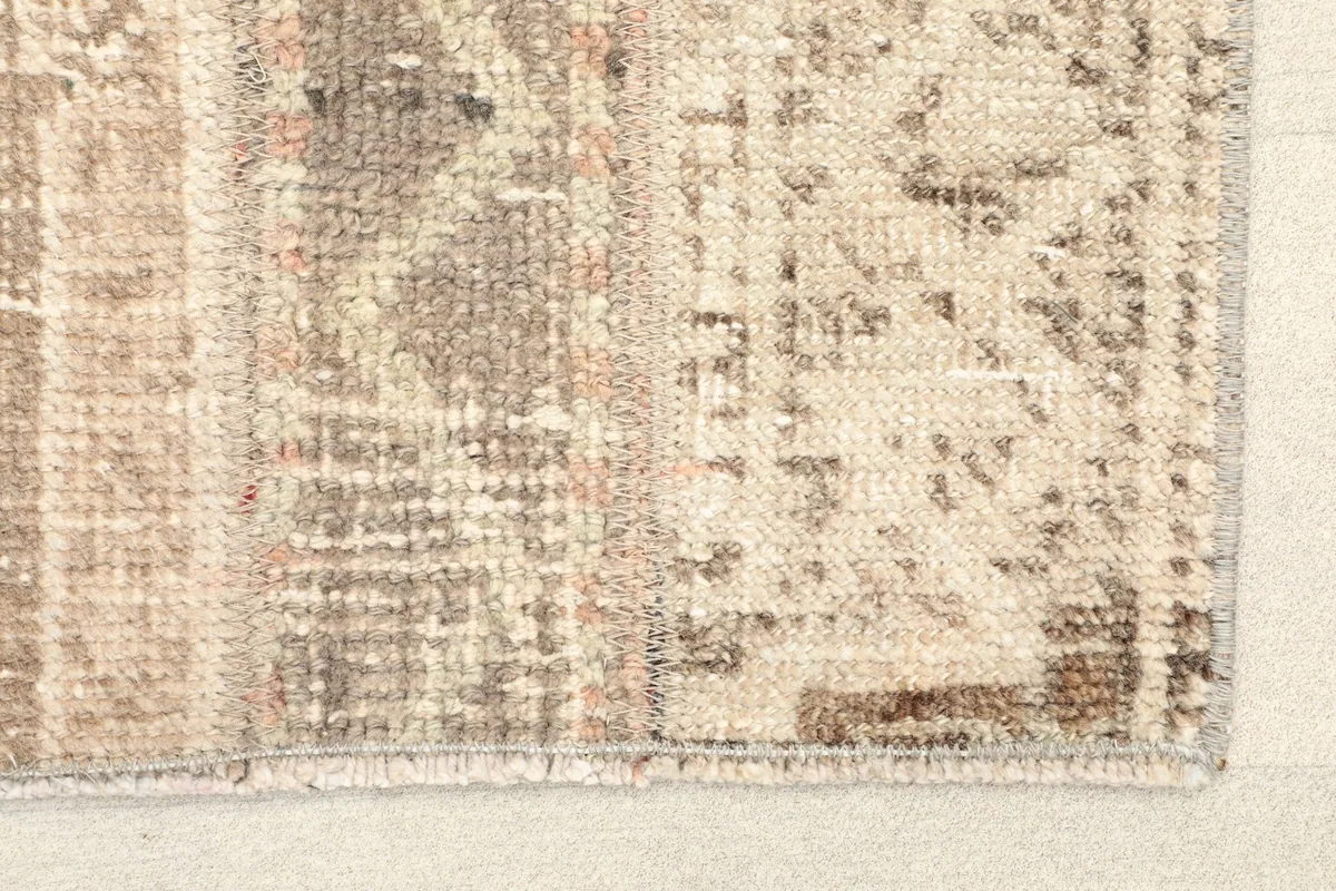 Close-up detail of the rug's corner, showing the worn pile and subtle color variations.