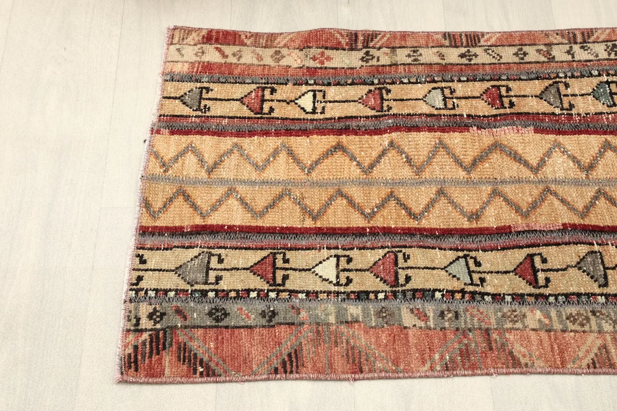 Angled shot of the rug's left side, showing the distinct color sections and motifs.