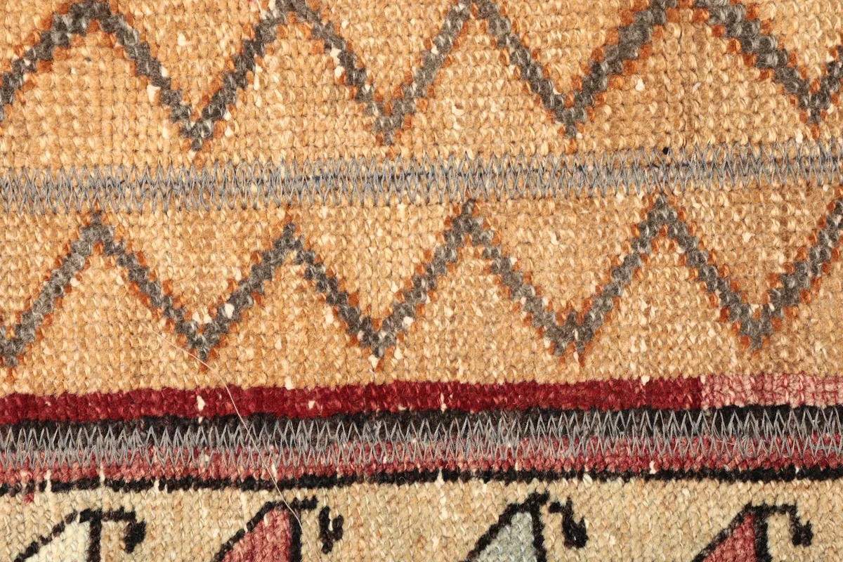Detailed view of the central beige stripe with zigzag patterns and adjacent red and gray bands.