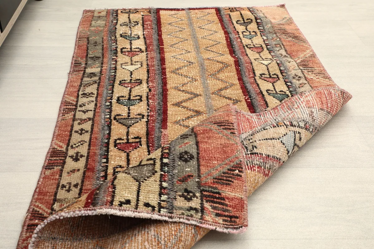 The rug partially folded, demonstrating its flexibility and the vintage wear on the pile.