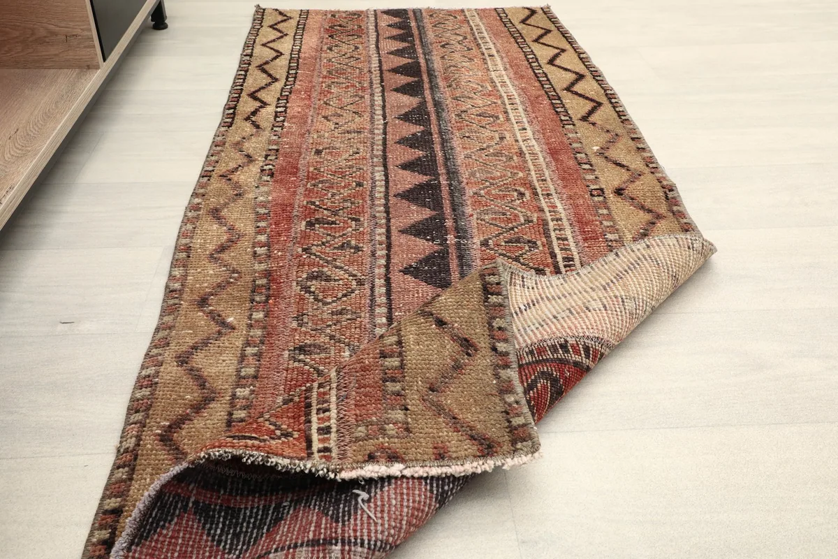 Rug partially folded, illustrating its flexibility and the texture of the low wool pile.