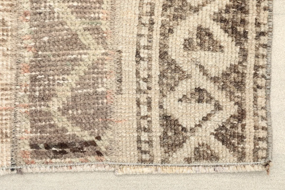 Close-up detail of the rug's low pile, highlighting the muted brown and beige geometric patterns