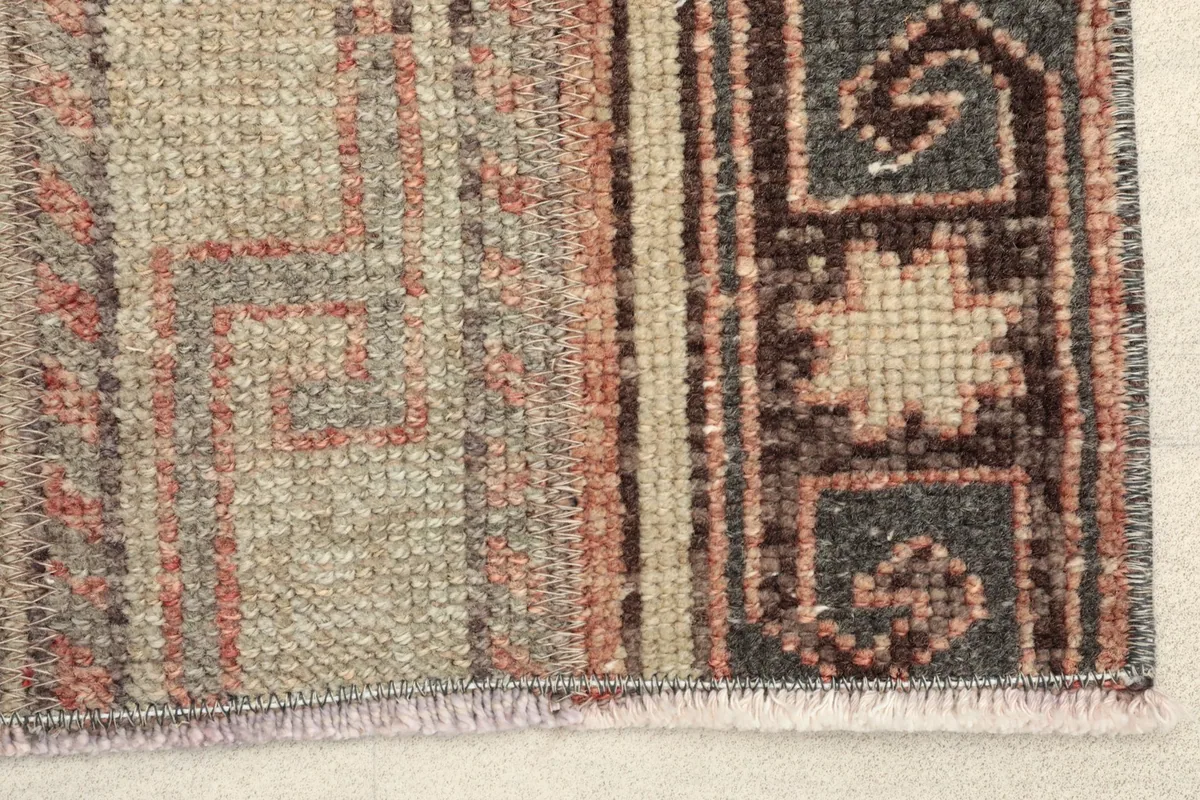 Close-up detail of the rug's edge, showing the low wool pile, cotton foundation, and subtle fringe.