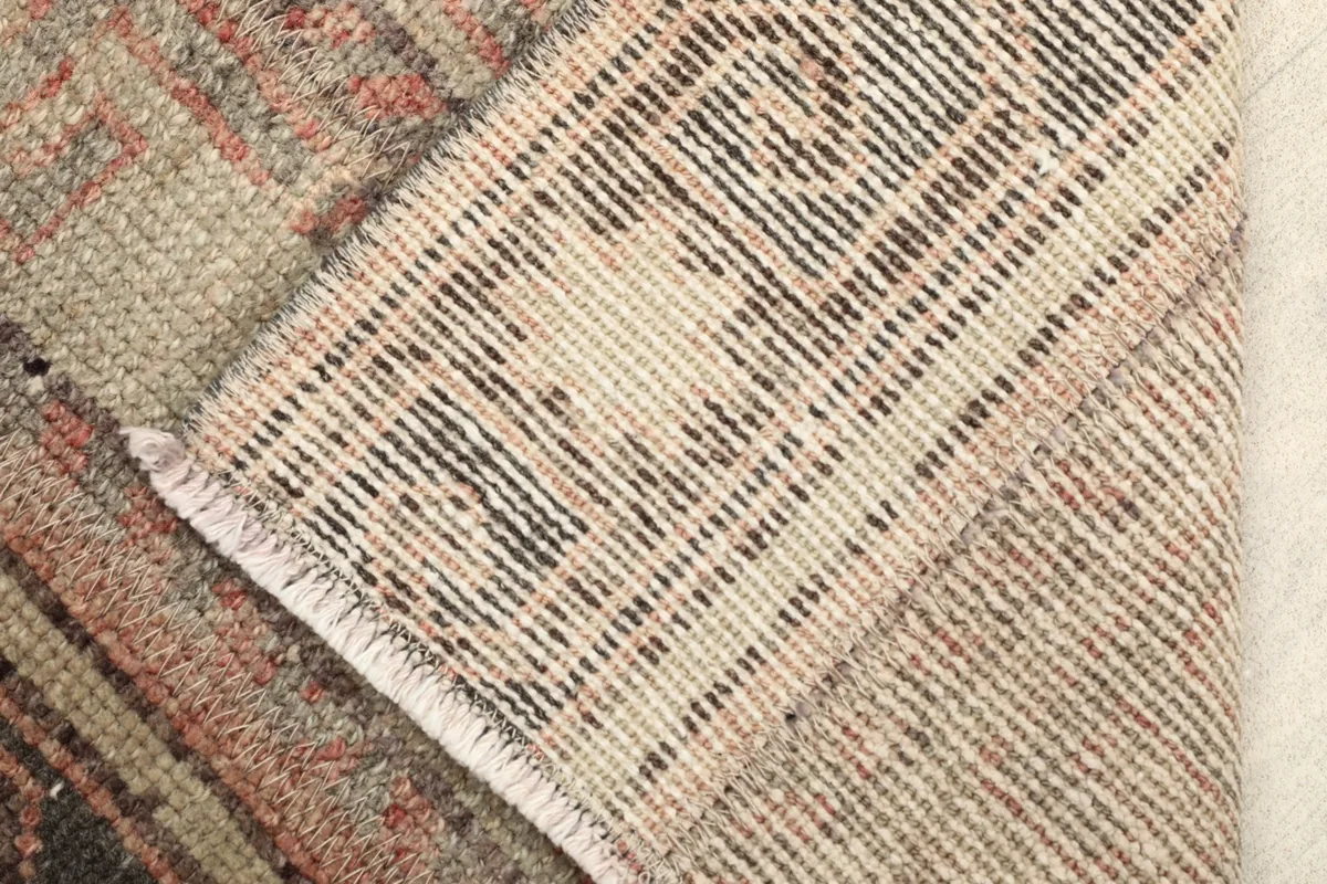 View of the rug's folded back, revealing the hand-knotted wool pile on a cotton foundation.