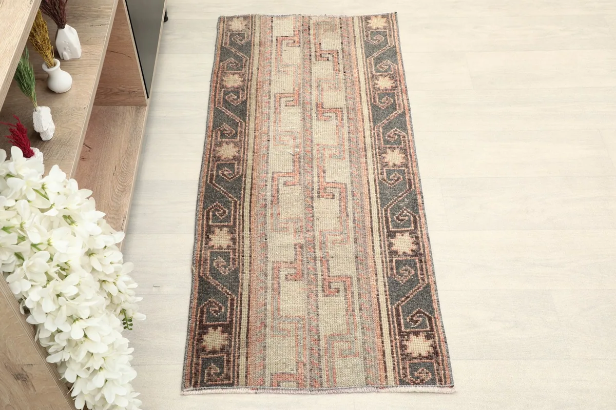 Overhead view of the hand-knotted vintage Anatolian rug, showcasing its beige field and charcoal geometric patterns.