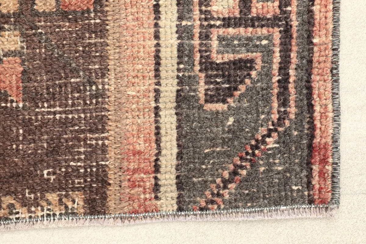 Close-up detail of the rug's edge, showing the gray border and brown field with subtle wear.