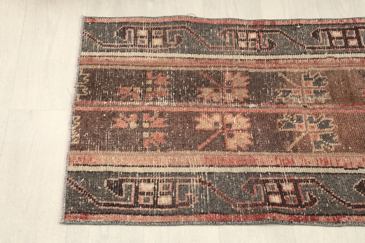View of the rug's side, focusing on the intricate gray border and central striped design.