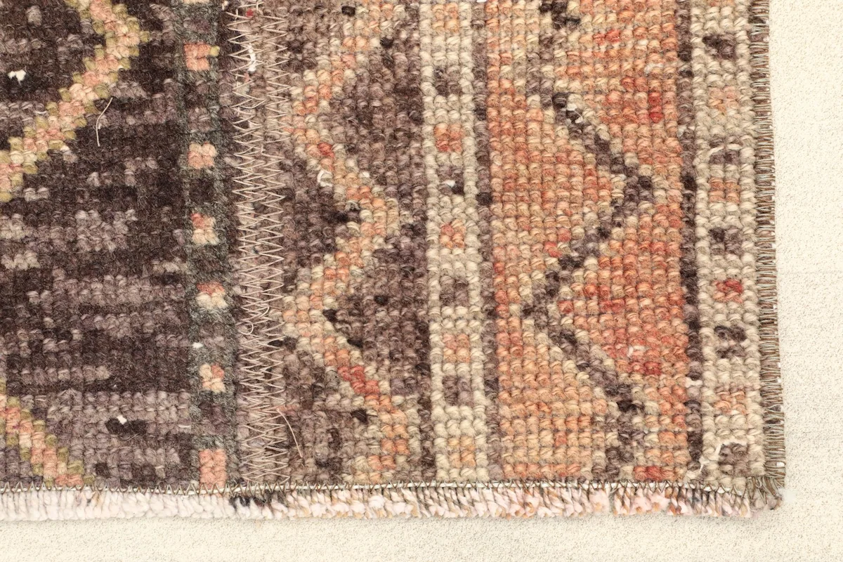 Close-up detail of one end of the runner, showing the fringe and woven edges with rust and brown tones.