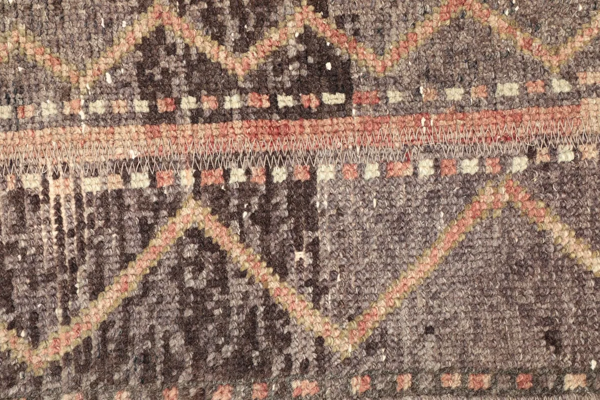 Detailed view of the low wool pile and intricate tribal patterns in brown, beige, and rust.