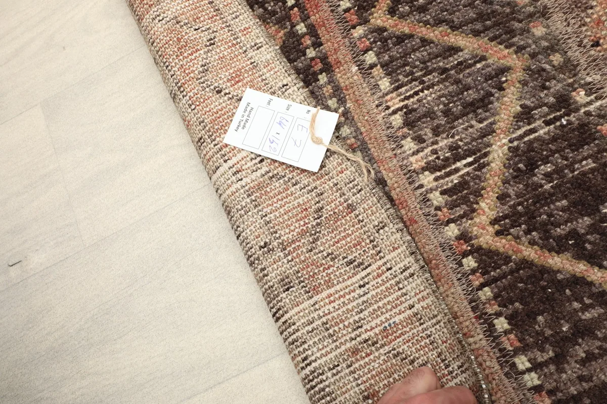 Close-up of the folded rug with a tag, showing the reverse side and the quality of the knotting.