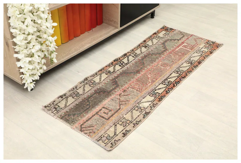 Full overhead view of the beige and rust vintage Anatolian runner on a white floor.