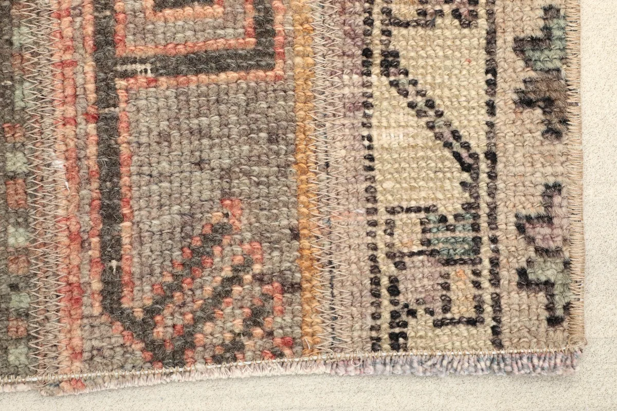 Close-up detail of the rug's texture and muted colors, showing the hand-knotted wool pile.