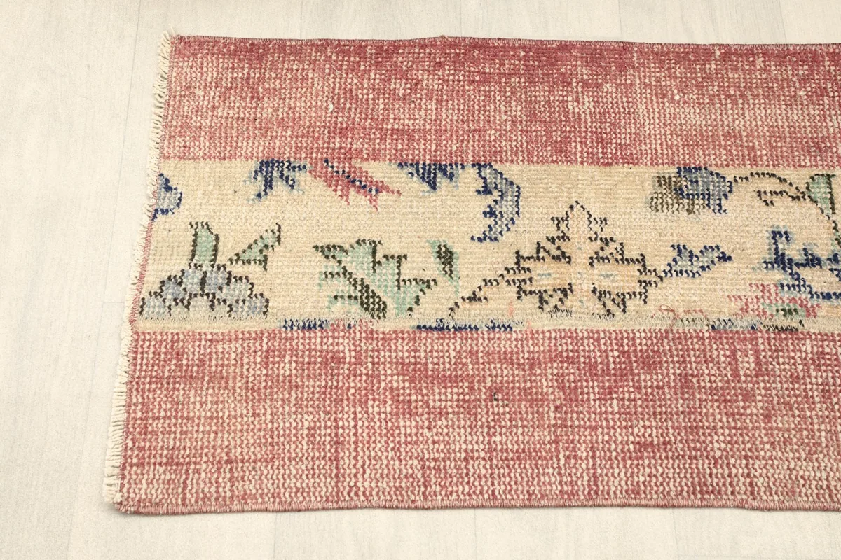 Overhead view of one end of the rug, showing the fringe and the transition from rose to beige