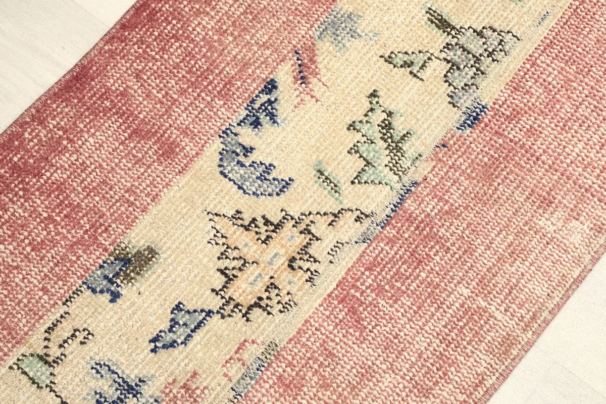 Angled view highlighting the texture and colors of the rose and beige sections of the rug.