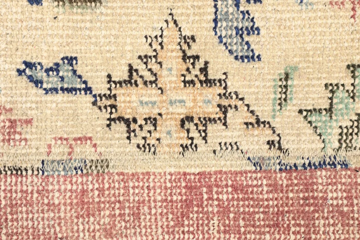 Detailed view of the floral and geometric motifs in blue, green, and black on the beige panel.