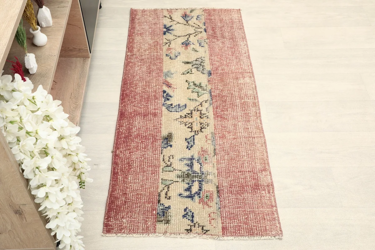 Overhead view of the rose area rug with a beige floral and geometric center.