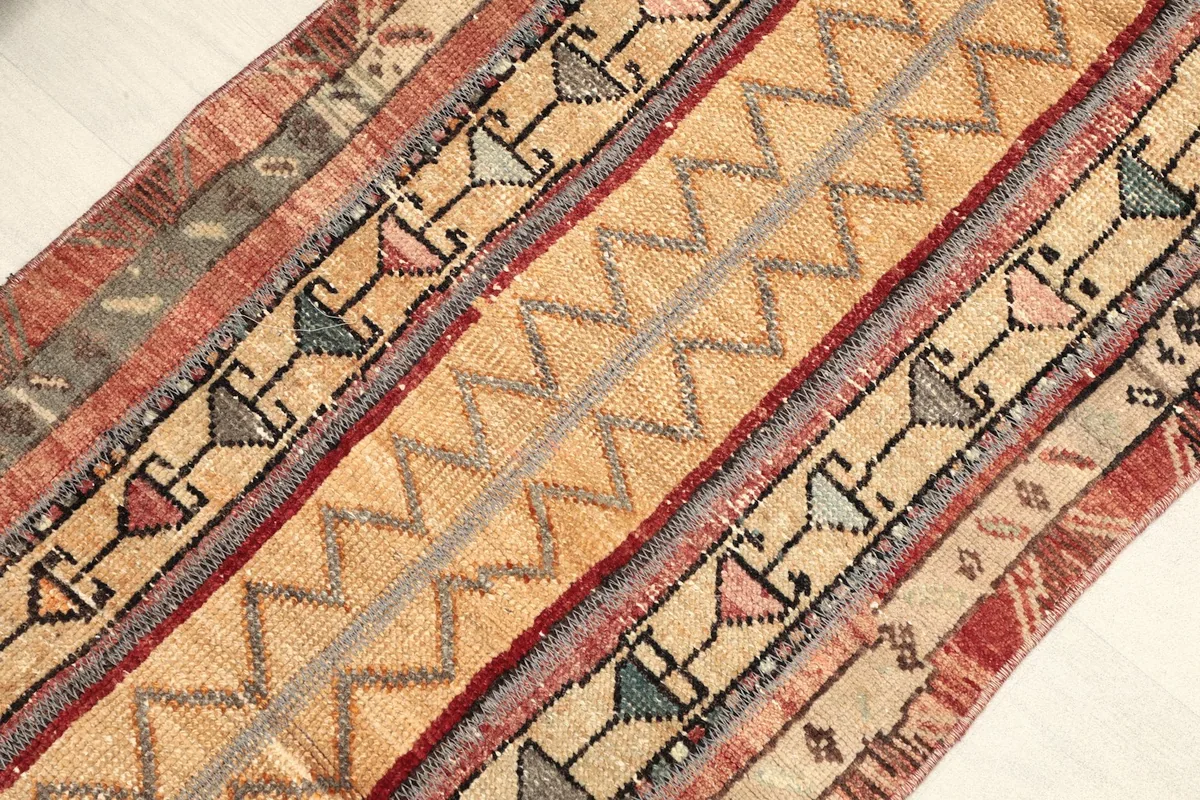 Angled view across the rug surface, revealing the geometric motifs within the tan and rust stripes.