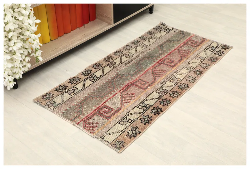 Full overhead view of the beige and red geometric tribal rug on a white floor.
