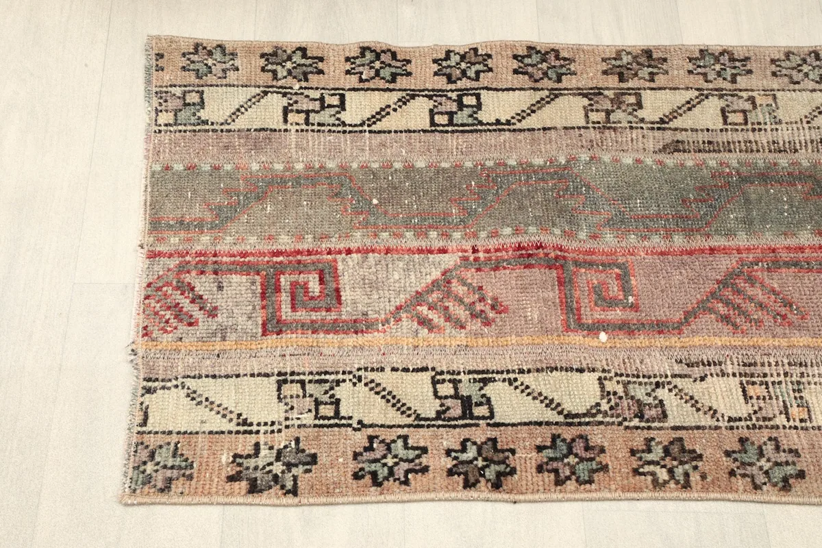 Upper section of the rug viewed from an angle, displaying the border-like motifs and central stripes.