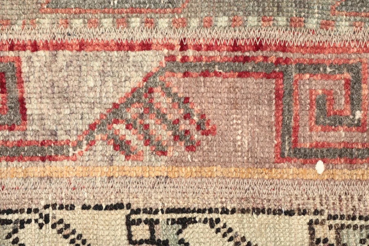 Detailed shot of a specific geometric motif and the subtle color shifts in the vintage wool.