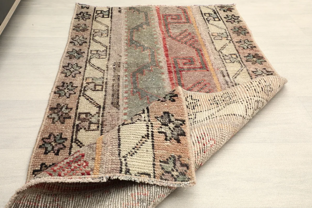 The rug partially folded, showing both the pile side and the foundation, indicating its flexibility.