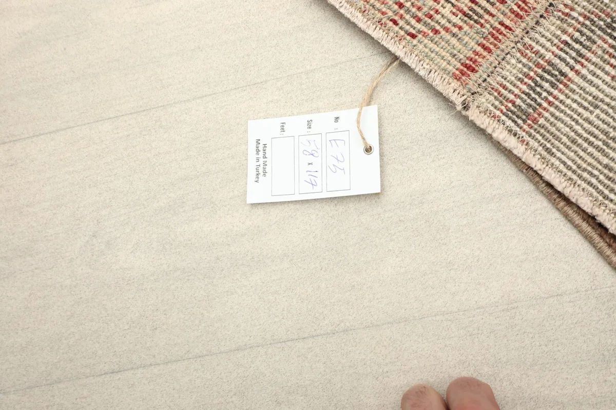 Tag with rug dimensions and details, placed next to a corner of the rug on a light wooden floor.