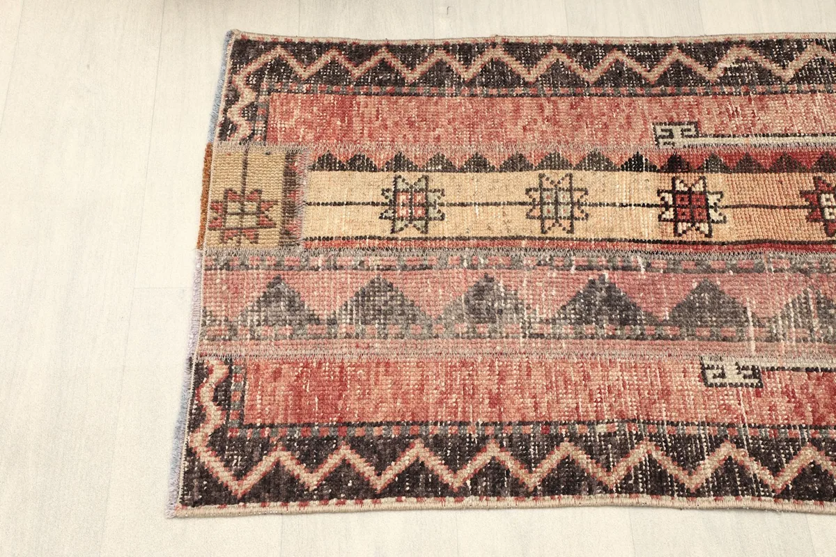 Partial angled view of the rug's top half, showing the rose field, beige stripe, and charcoal border patterns.