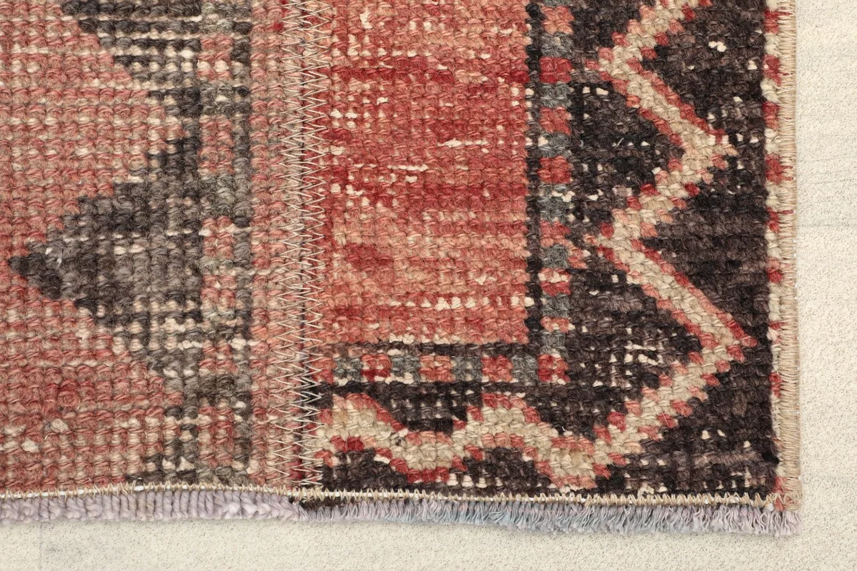 Close-up detail of the rug's border and field, showing the wool pile texture and distressed areas.