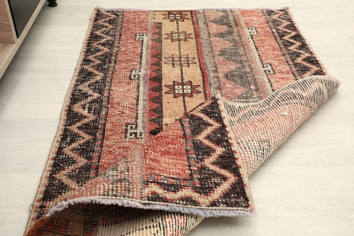 The rug partially folded, displaying both the pile side and the detailed hand-knotted reverse.