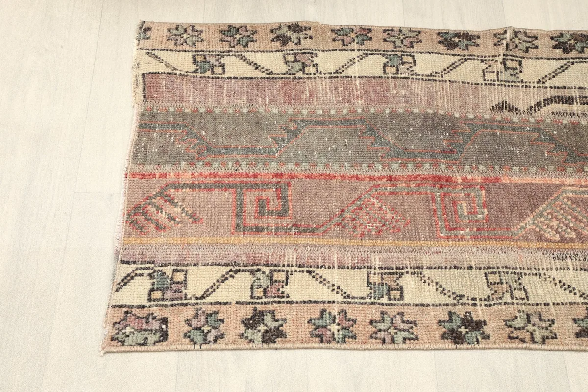 Corner view of the rug, showing the blend of beige, brown, and red hues in the patchwork.