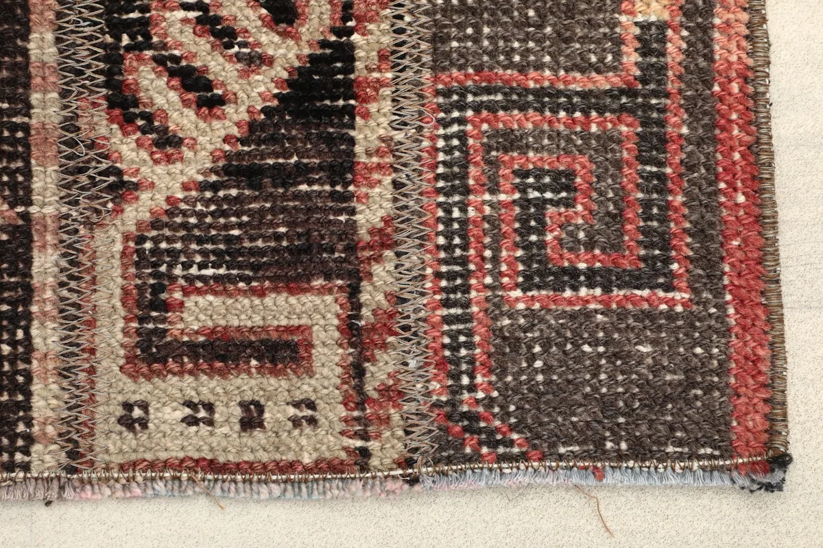 Close-up detail of the hand-knotted wool pile and tribal motifs, showing slight wear and color variations.