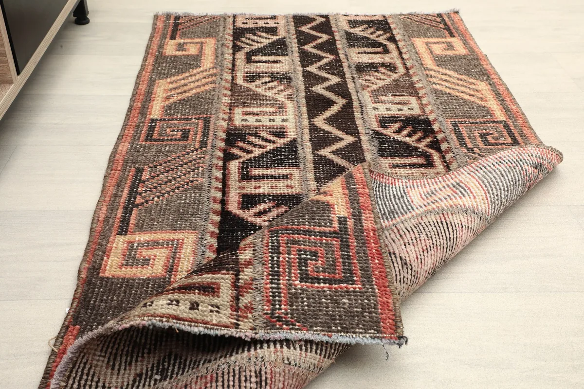 Rug partially folded, showing the flexibility and thickness of the vintage wool pile.