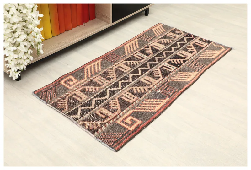 Full top view of the 2x4 brown, tan, and rust tribal geometric area rug on a light floor, styled in a room.