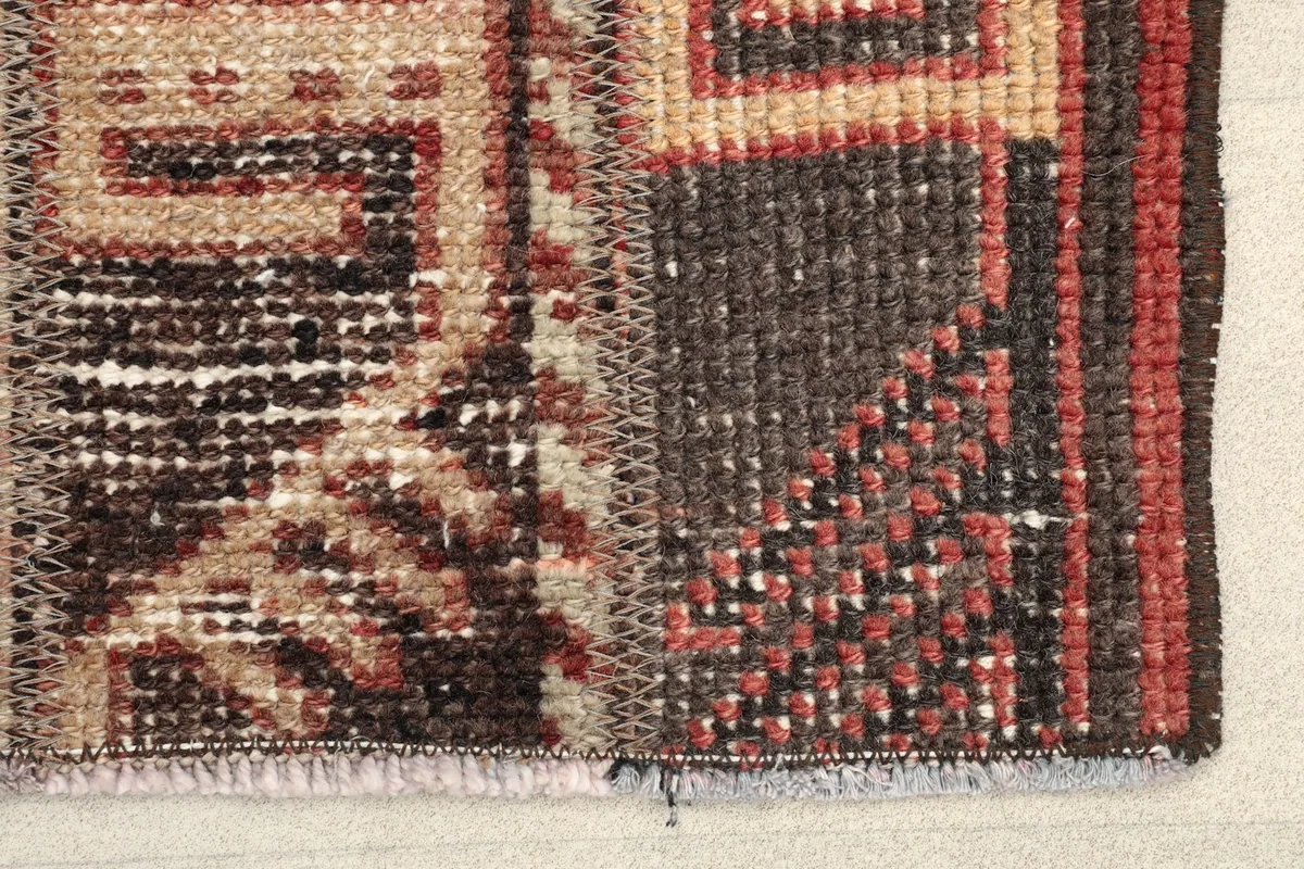 Close-up detail of the rug's edge, showing the hand-knotted wool pile, cotton foundation, and subtle color variations.