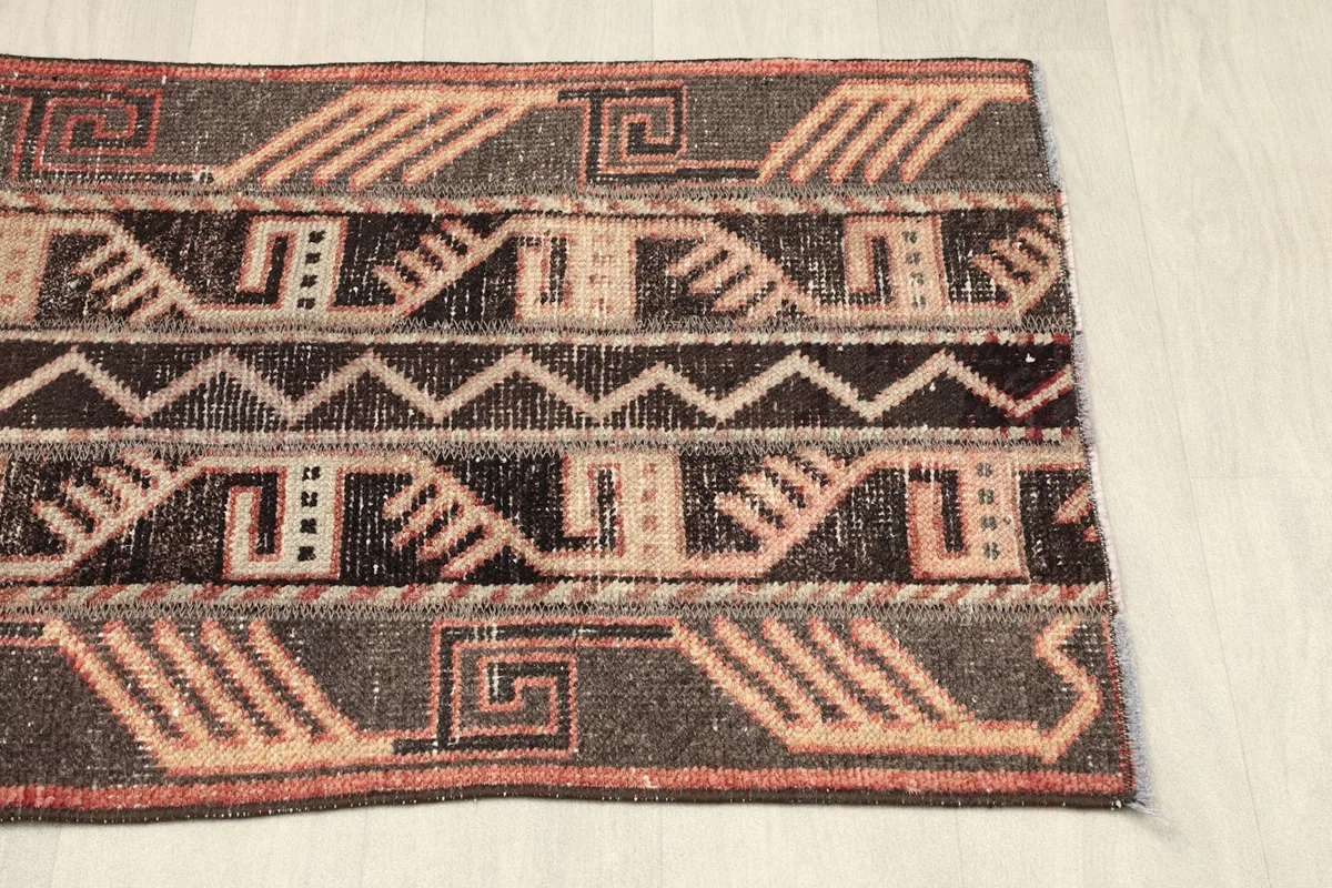 Close-up of the rug's right end, showcasing the varied tribal patterns and the subtle rust and brown tones.