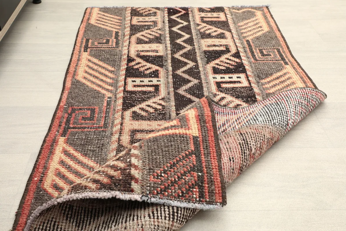 The rug folded to show both the patterned top and the detailed back, emphasizing its construction and flexibility.
