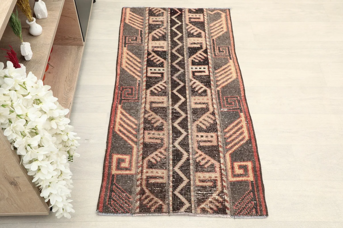 Overhead view of the entire hand-knotted wool area rug, displaying its brown, tan, and rust geometric patterns.