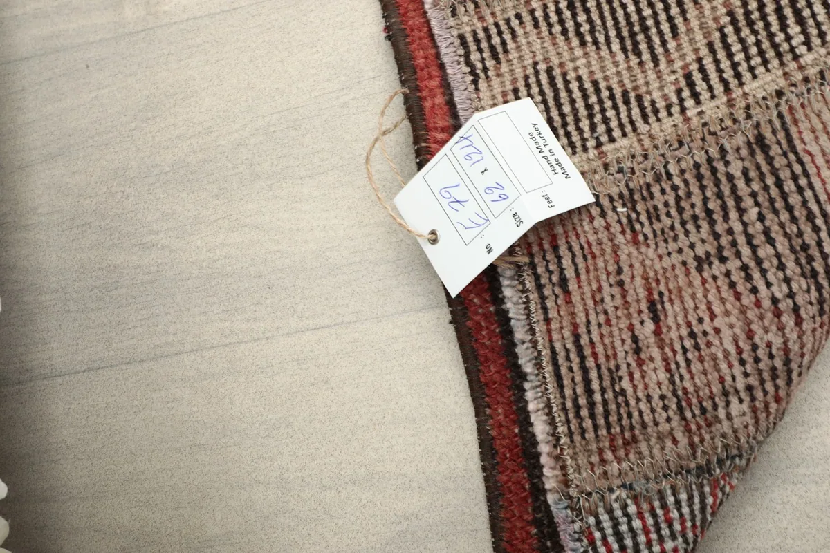 A partial view of the rug with a size tag, showing the reverse side and the hand-knotted wool and cotton materials.