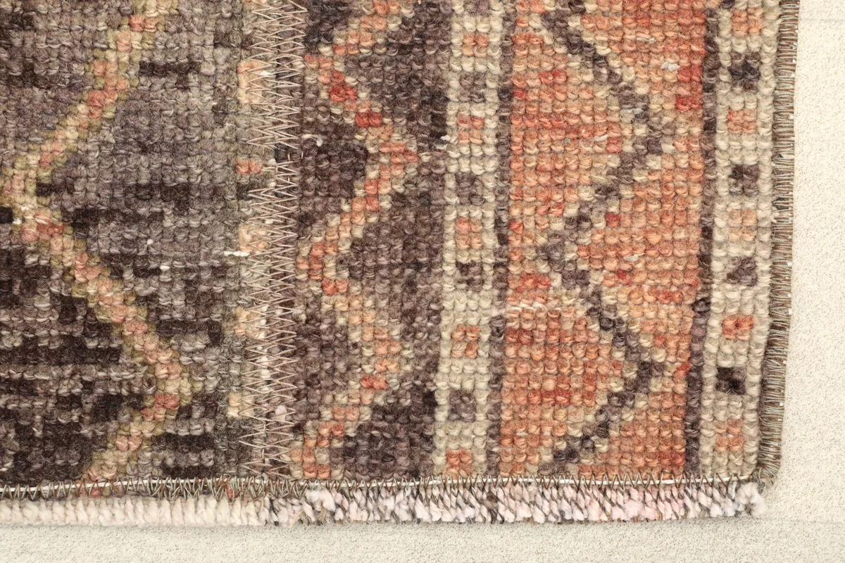 Close-up detail of the rug's edge, showing the hand-knotted wool pile and cotton foundation.