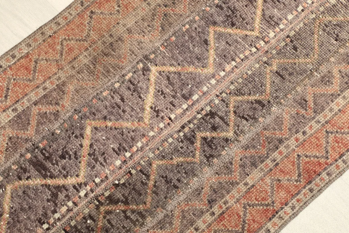 Angled close-up of the rug's brown and rust geometric zigzag patterns and texture.