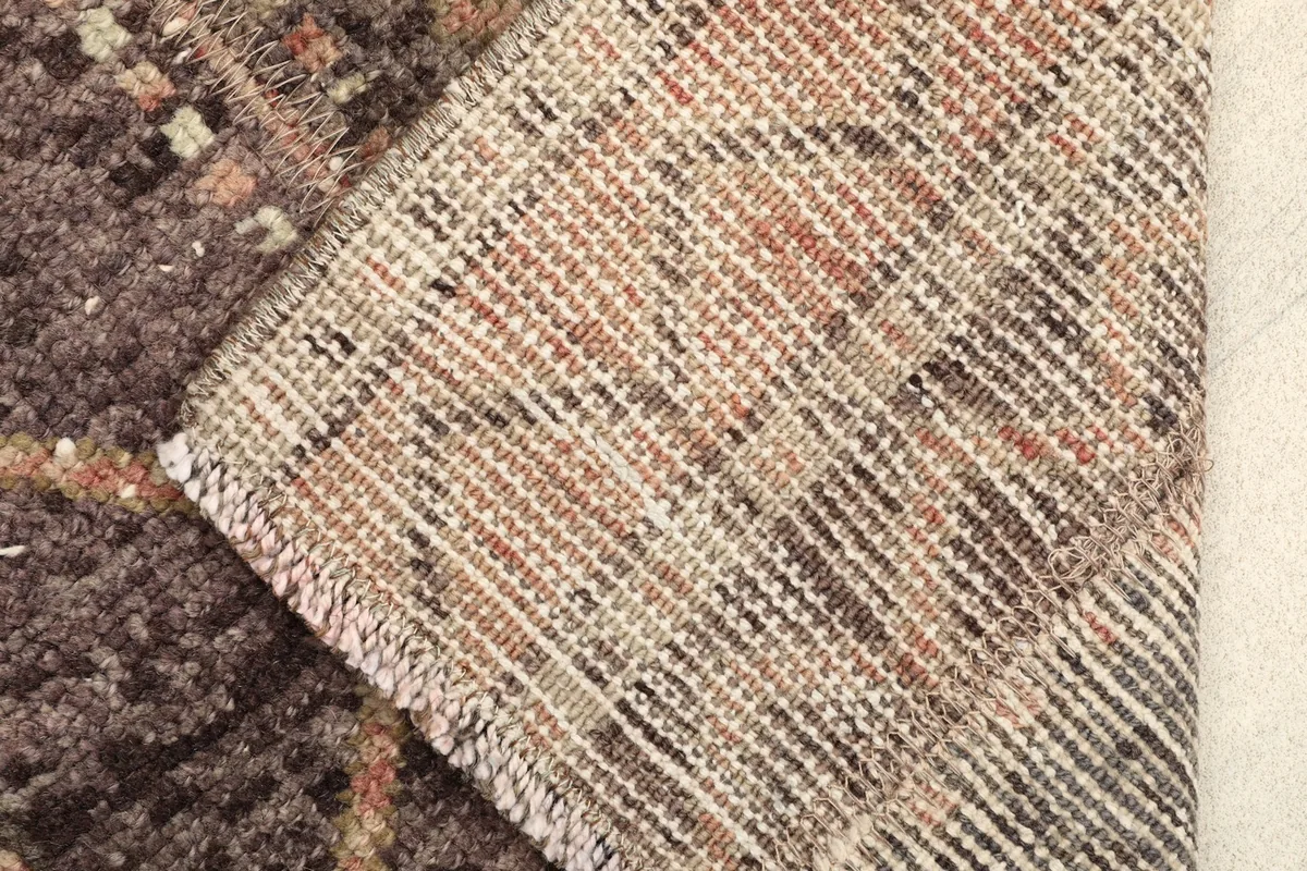 View of the rug's back and folded corner, revealing the cotton foundation and tight weave.