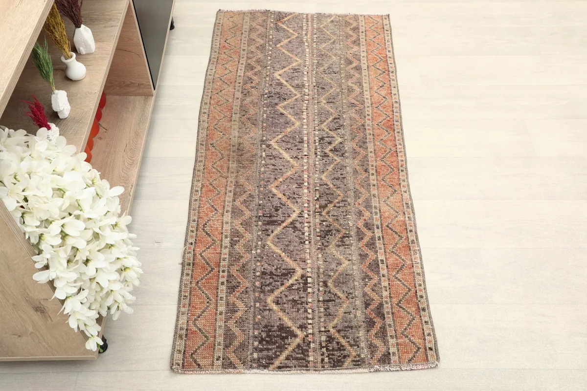 Overhead view of the brown and rust tribal rug, showing its geometric patterns and colors.