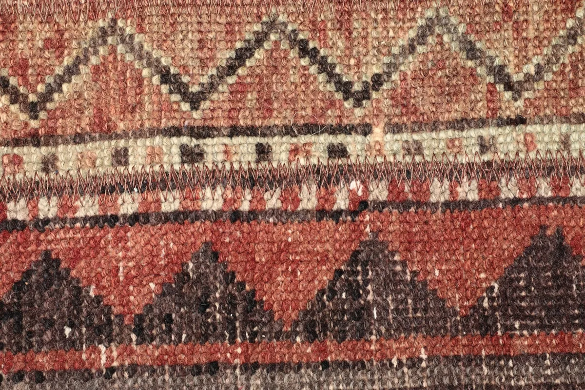 Extreme close-up of the hand-knotted wool pile, revealing the detailed zigzag and linear geometric designs.