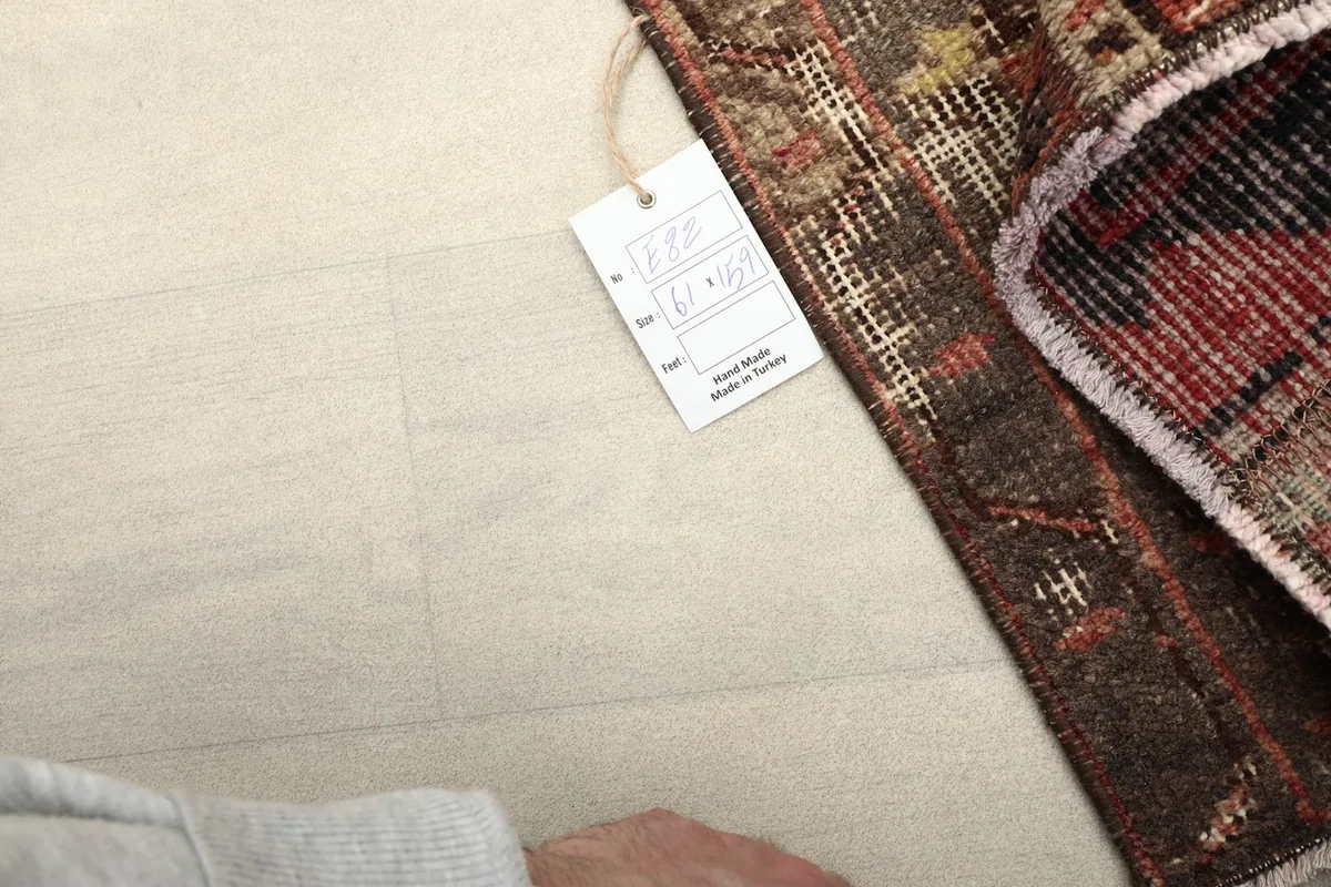 View of the rug's cotton foundation and a product tag, indicating its origin and hand-knotted construction.