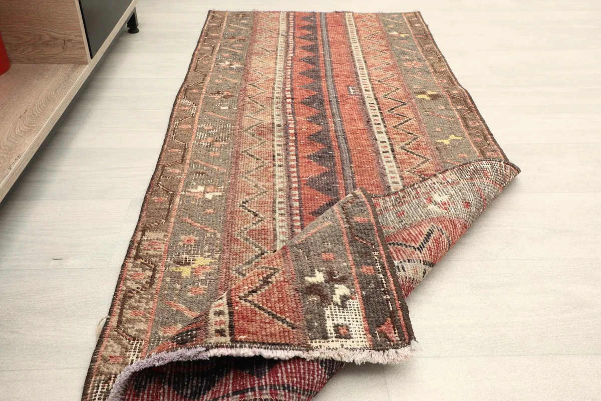The runner rug partially folded, showing the flexibility and the reverse side of the hand-knotted cotton foundation.