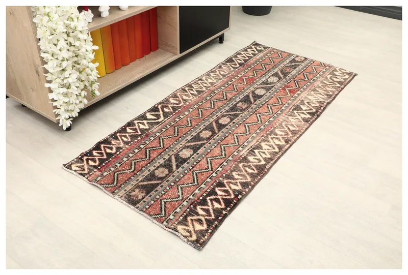 Full overhead view of the rust, black, and ivory tribal geometric rug on a light floor.