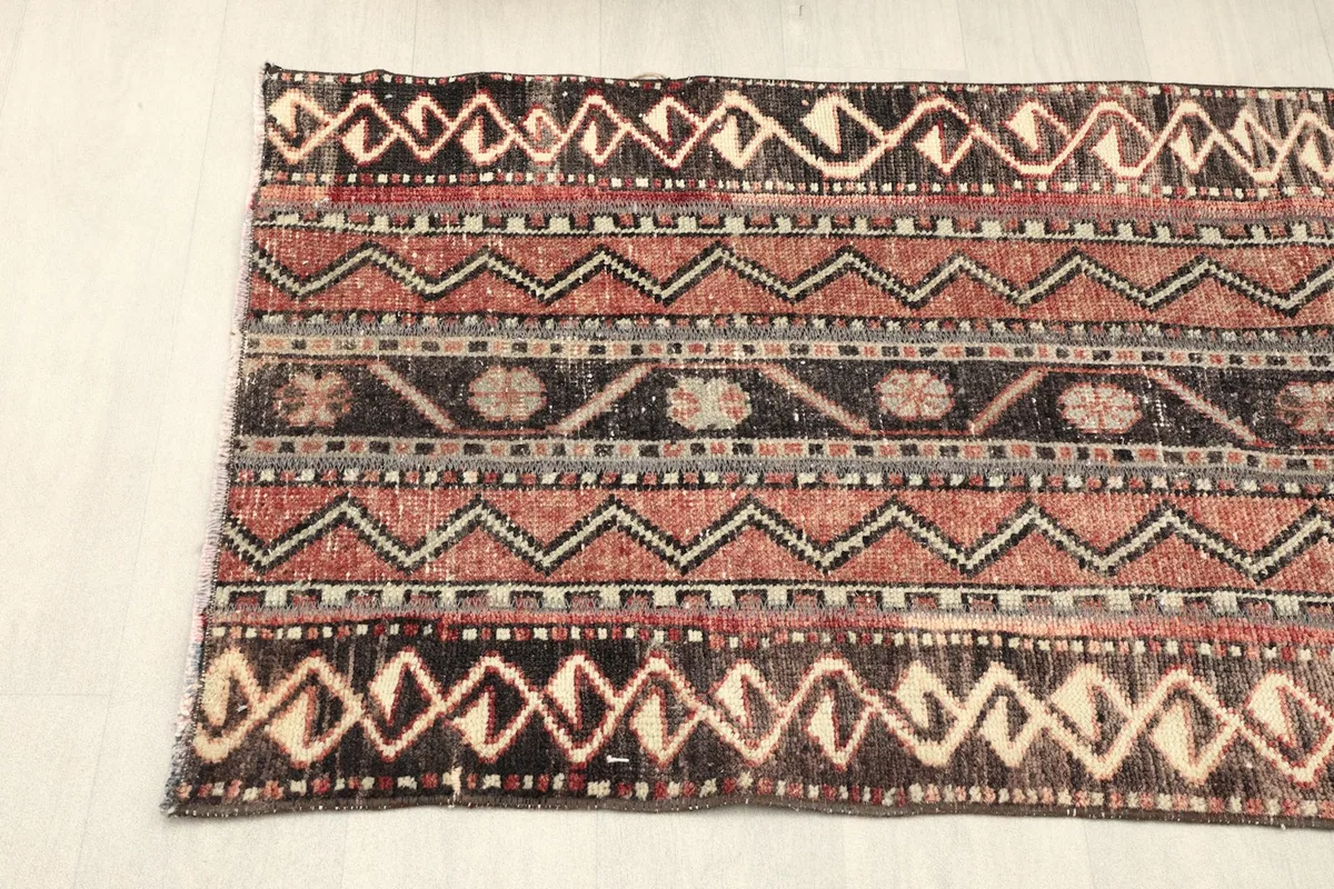 View of the rug from one side, displaying the horizontal bands of tribal and geometric designs.