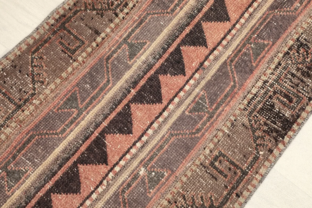 Angled view showcasing the rug's texture and the blend of brown, rust, and black geometric patterns.