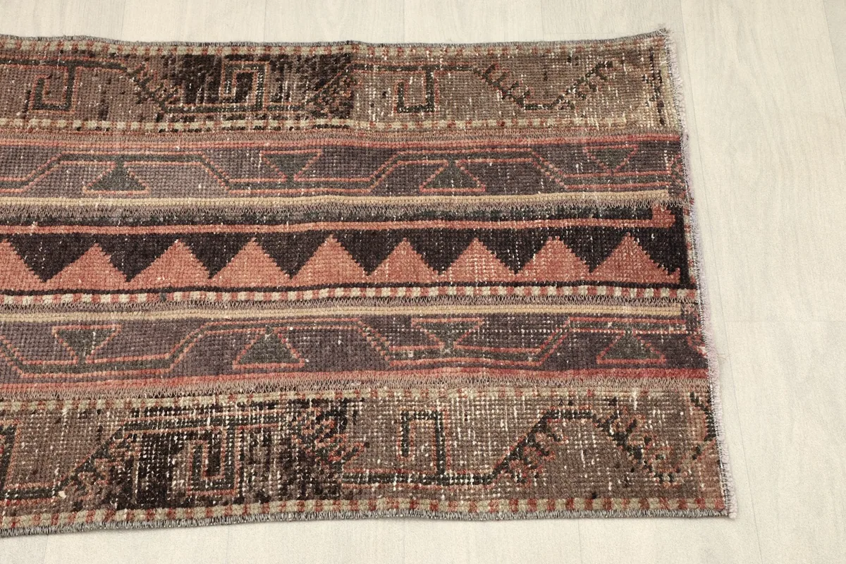 Partial view of the rug from the opposite end, highlighting the distressed wool pile and patterns.